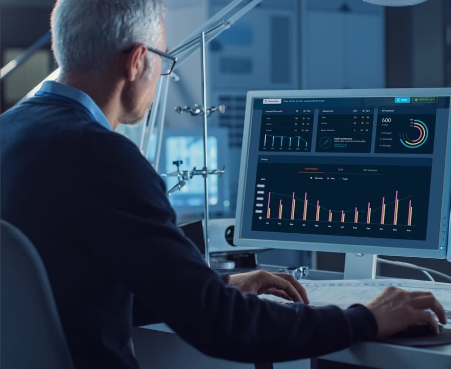Person in dark suit analysing data on computer monitor displaying colourful graphs and performance metrics.