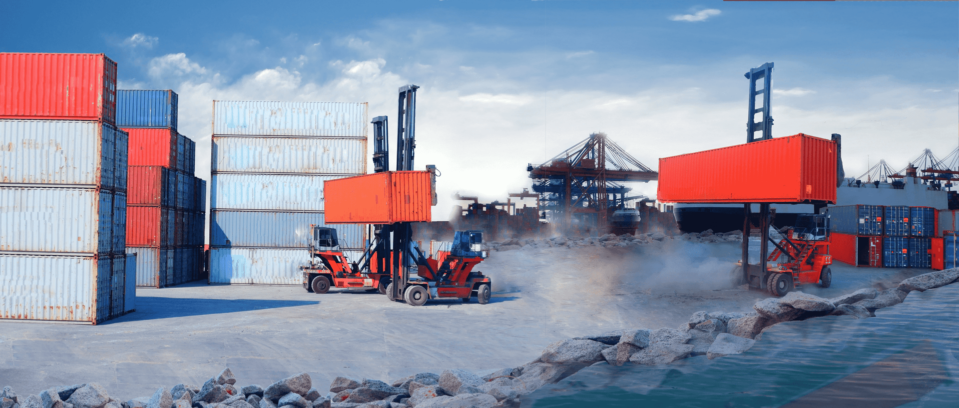 Busy shipping port with forklifts moving colourful cargo containers, cranes visible in background against blue sky.