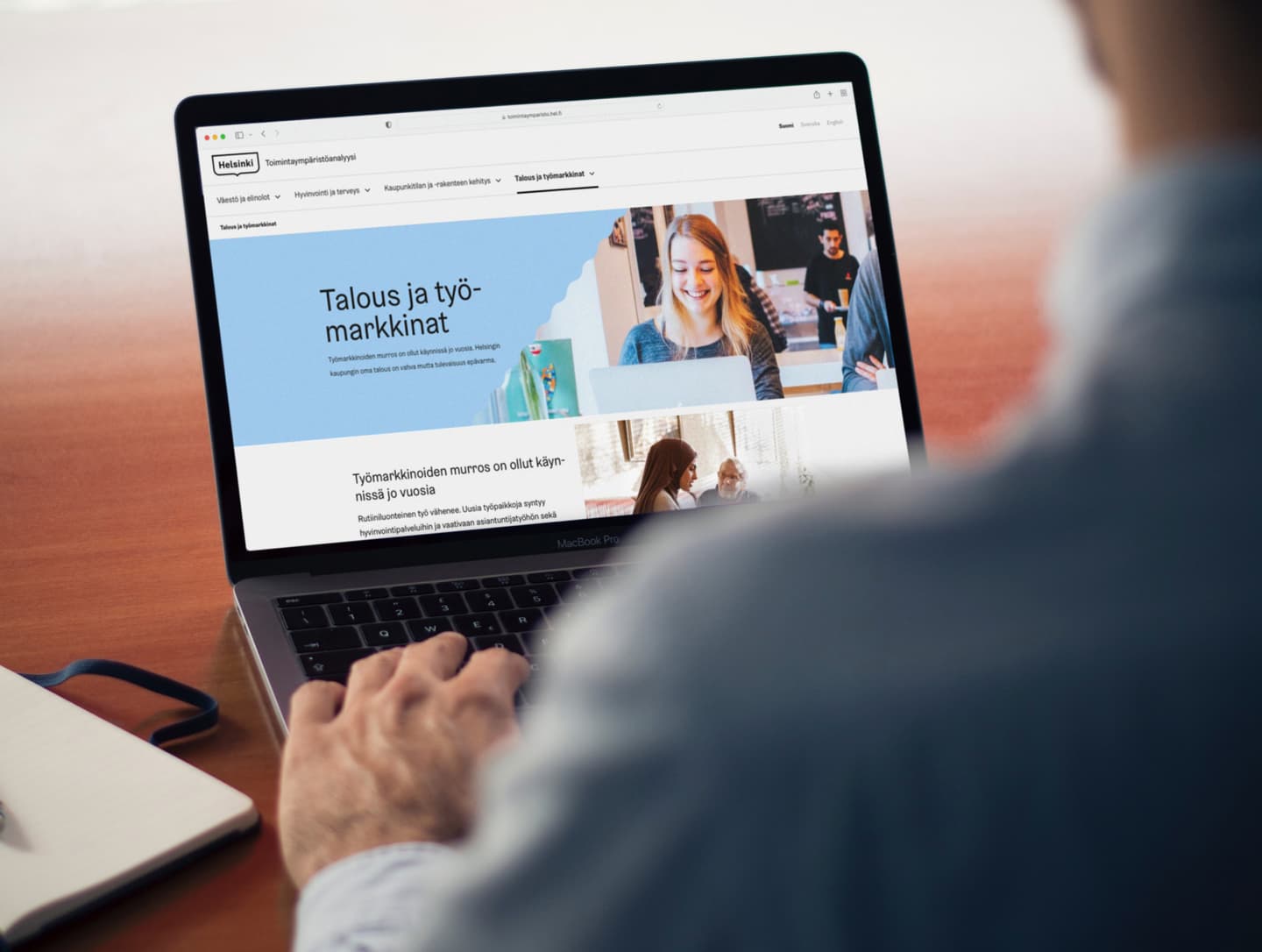 Person browsing Helsinki city website on a MacBook Pro, viewing a page about economy and job markets in Finnish.